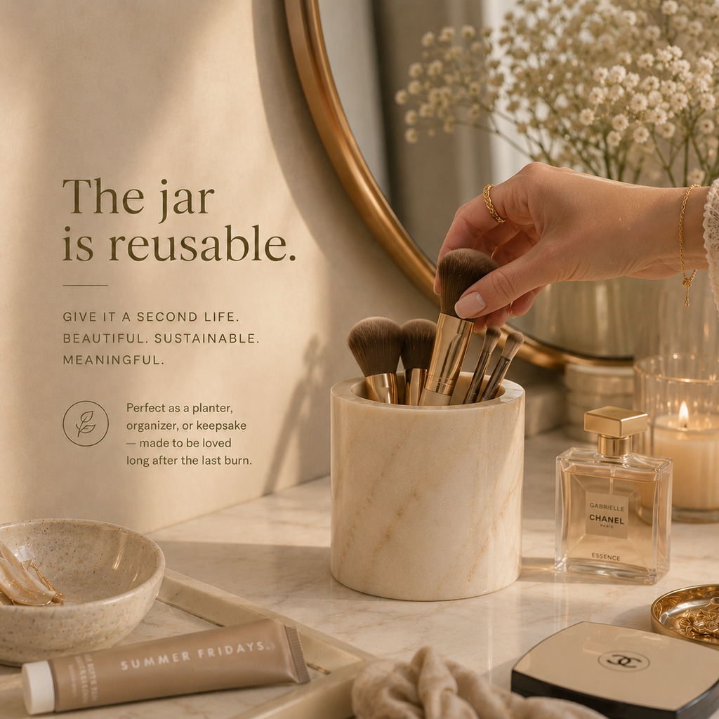 Hand holding makeup brushes in a reusable jar on a vanity with decorative items. Reusable natural marble candle jar by IVARO designed as a lasting luxury home decor object